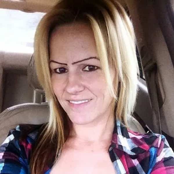 Woman in a car wearing very thin high arched eyebrows drawn in a single line.