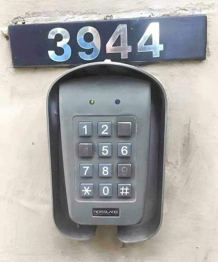 A security funny fail showing a wall-mounted keypad for building entry. The metal numbers "3944" are bolted directly above the keypad, essentially handing the secret code to any stranger walking by.