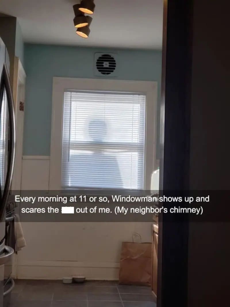 A kitchen window where the silhouette of a neighbor's chimney looks like a person standing outside.