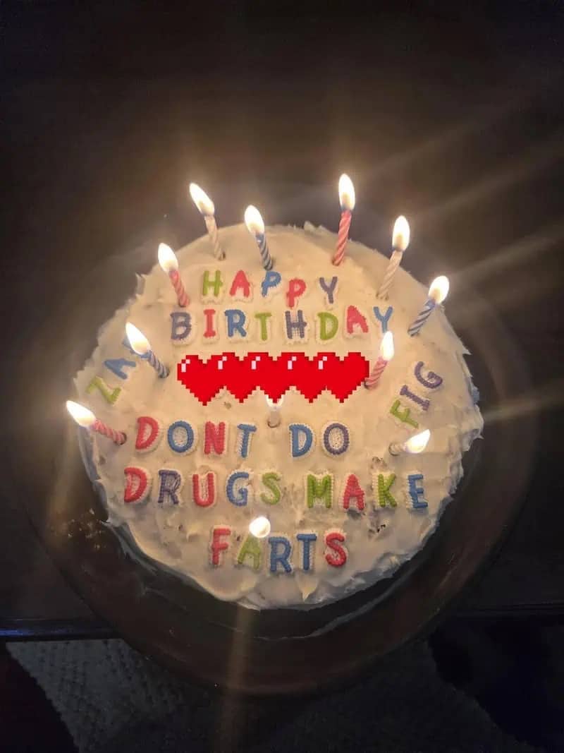 Birthday cake with candles and text reading don't do drugs make farts with pixelated heart graphics.