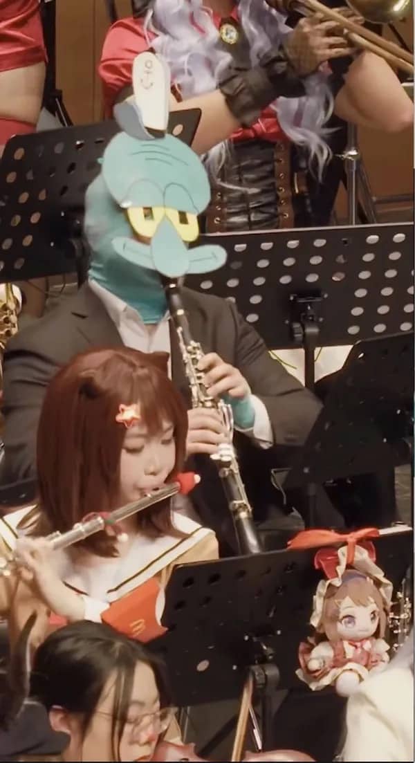 Orchestra performer wearing Squidward mask plays clarinet surrounded by cosplaying musicians