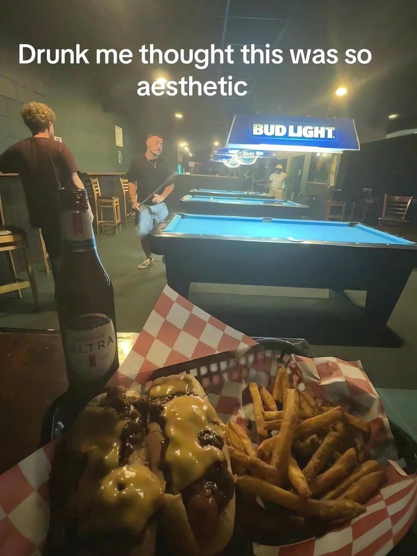 High-angle photo of chili cheese dogs and fries at a pool hall with "aesthetic" text overlay.