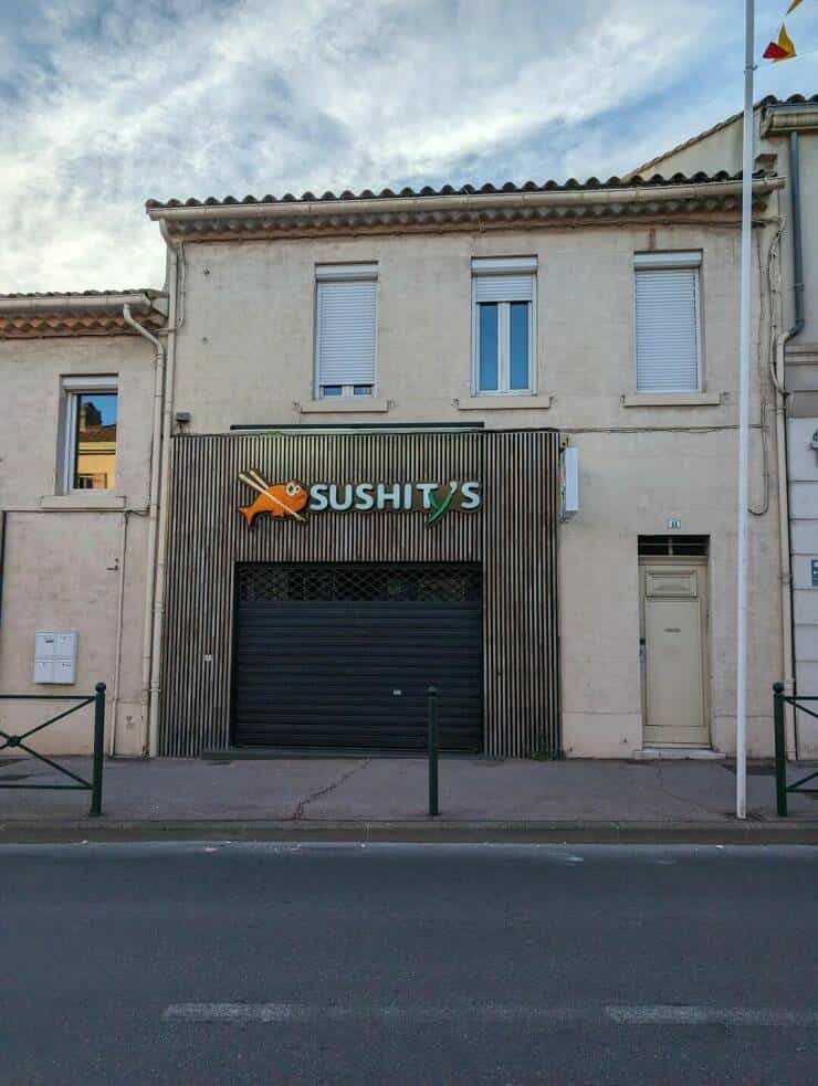 Funny storefront sign for a restaurant named Sushit's with a fish logo and green underline.