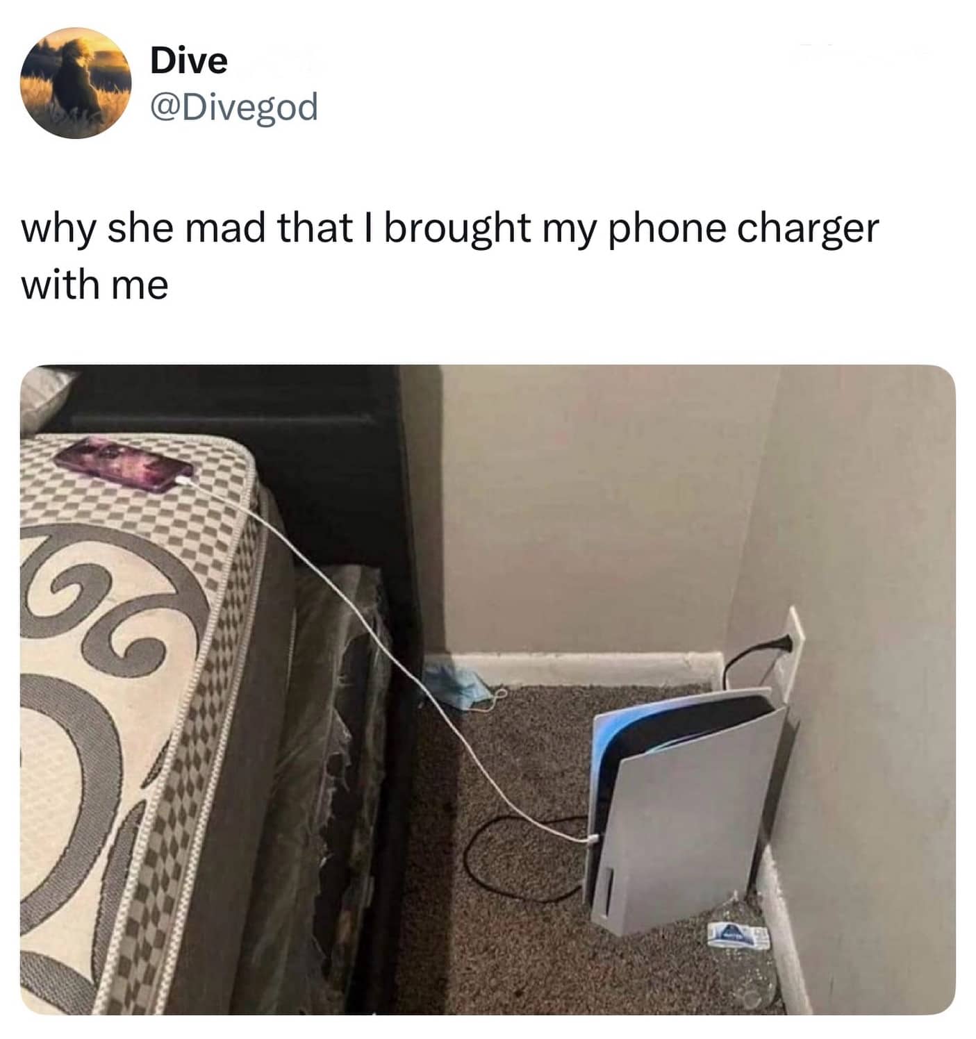 Phone charging from a PlayStation 5 console on the floor next to a bare mattress.
