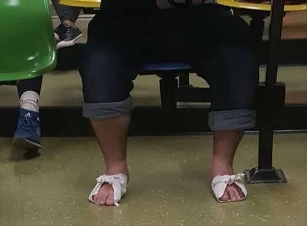 A person wearing makeshift sandals made of white napkins or paper held together by ties.