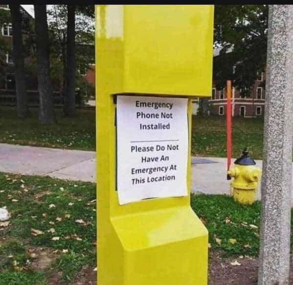 A peak example of corporate logic: a funny sign taped inside a yellow emergency call box. The typed message bluntly states, "Emergency Phone Not Installed. Please Do Not Have An Emergency At This Location," offering no help to someone in crisis.