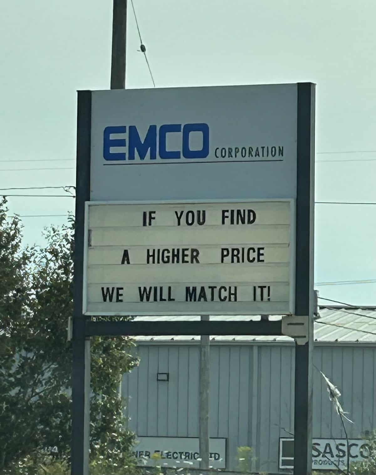 A business sign for EMCO Corporation offers a confusingly bold guarantee to "match" any higher prices a customer might find elsewhere.