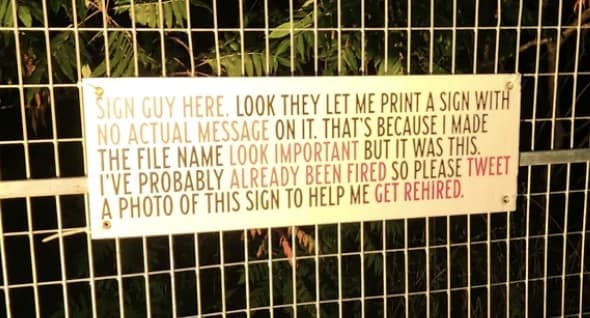 white banner attached to a chain-link fence contains a humorous plea from a "Sign Guy" who admitted to printing a pointless message just to see if he could.