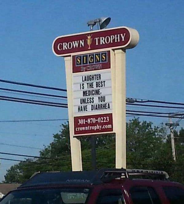 A funny sign on a tall marquee for "Crown Trophy." It offers a piece of gastrointestinal wisdom to those passing by: "LAUGHTER IS THE BEST MEDICINE. UNLESS YOU HAVE DIARRHEA."