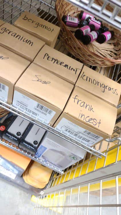 warehouse shelf featuring boxes of essential oils like bergamot and sage, but one box stands out with a cringeworthy funny spelling mistake labeling "frankincense" as "frank incest."