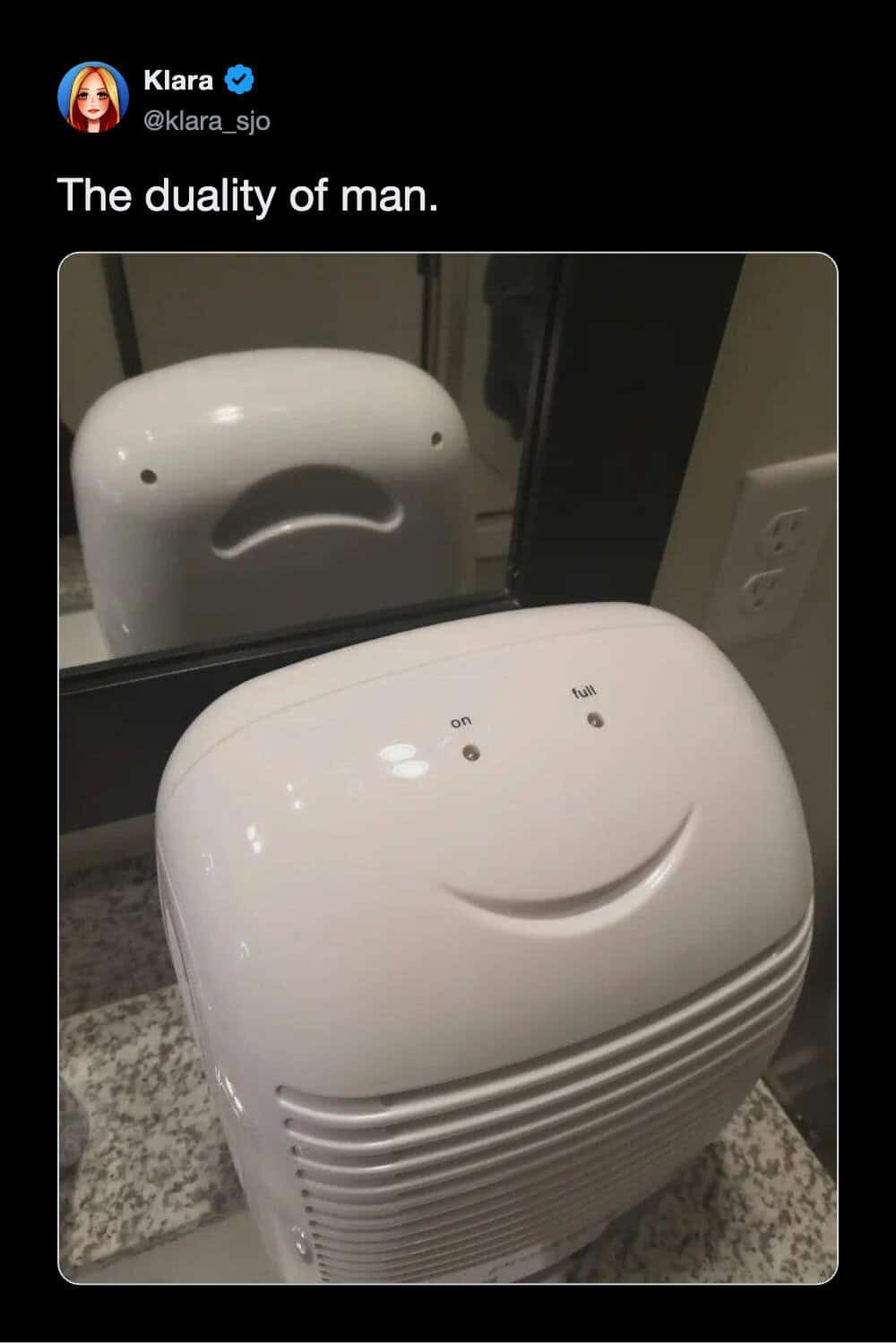 A visual funny tweet titled the duality of man, showing a white dehumidifier that looks like a cute smiling face from the front, while its reflection in the mirror reveals a deeply distressed screaming face, making it one of the funniest tweets about pareidolia.