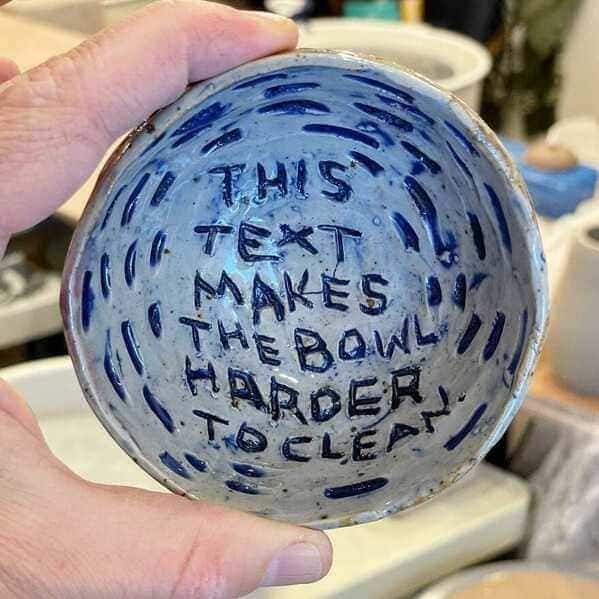 A small ceramic bowl with the handwritten message "This text makes the bowl harder to clean."