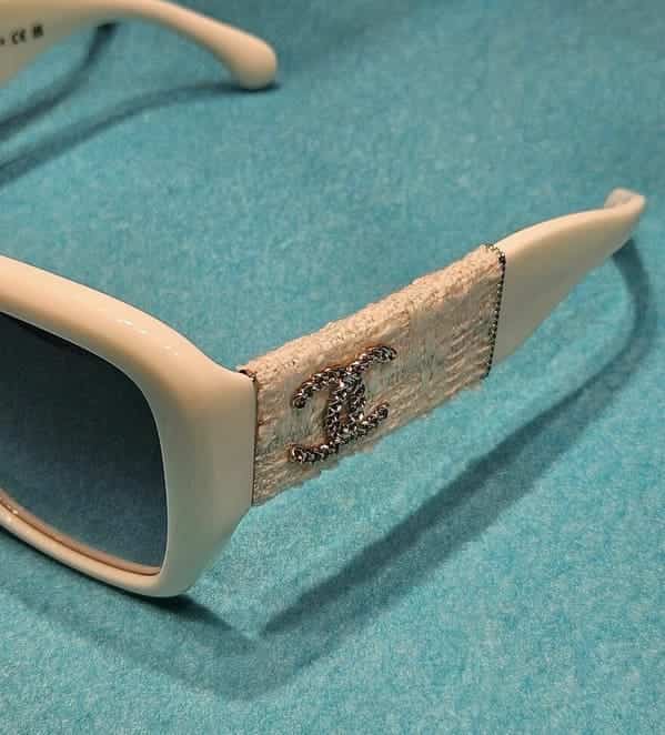 Luxury sunglasses with a white frame featuring a porous, light-colored fabric wrap on the temple.