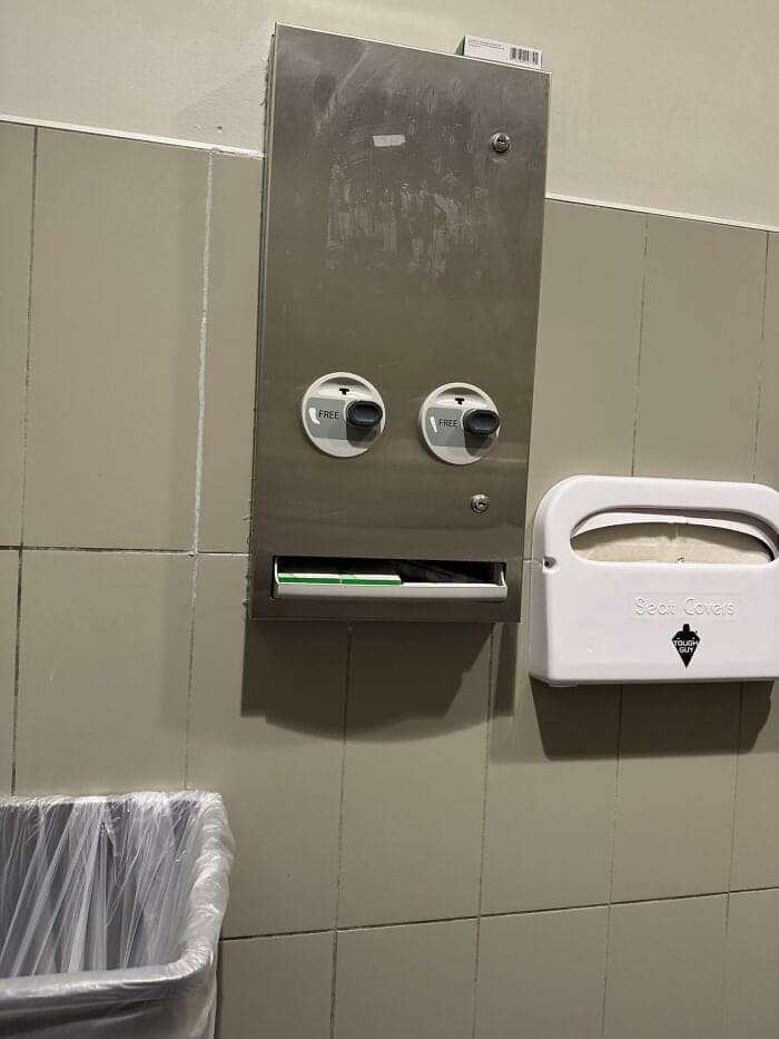 A brilliant spot of inanimate objects with faces featuring a stainless steel bathroom dispenser with two black turn-knobs and a wide dispensing slot that form a classic, slightly surprised robot expression.