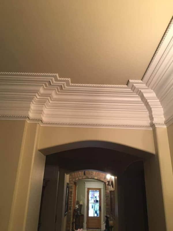 Excessively thick and tiered crown molding that descends awkwardly low over a standard interior archway.