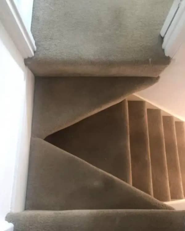Looking down a carpeted staircase where the landing is cut into sharp, narrow triangular points.