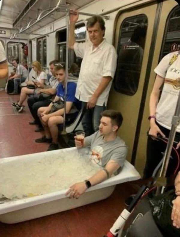 highly absurd internet meme capturing peak public transit energy, showing a man casually riding the subway while sitting inside a literal bathtub full of ice water and enjoying a beer, a surreal highlight of this meme dump