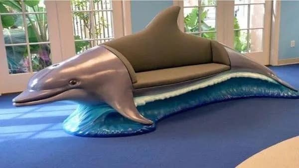 A bizarre and unexplained piece of living room furniture shaped exactly like a dolphin riding a blue ocean wave serving as a perfectly weird image in this meme dump.