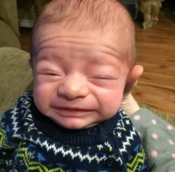 Crying baby with prominent forehead wrinkles looking like they are stressed about their mortgage and taxes.