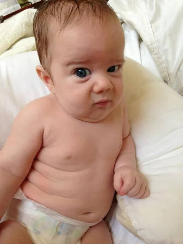 Infinitesimally small baby with visible rolls and a side-eye expression of pure existential judgment.
