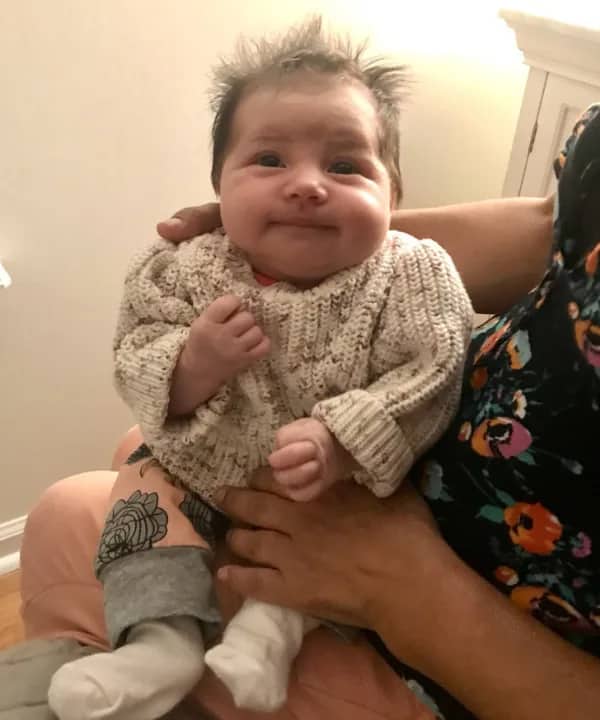 Content baby in a cable knit sweater with wild hair looking like a friendly neighborhood grandmother.