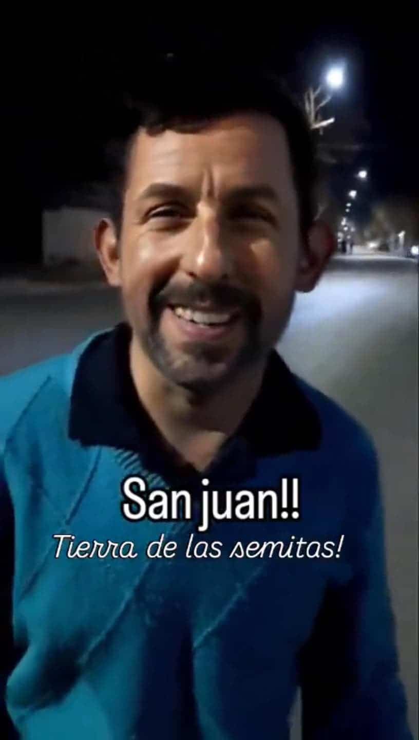 A man smiling at night in a blue shirt, bearing a striking resemblance to Happy Gilmore.