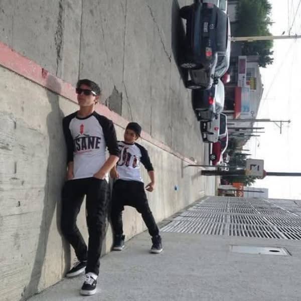 Two boys posing on a sidewalk with a forced perspective making them appear to lean sideways.