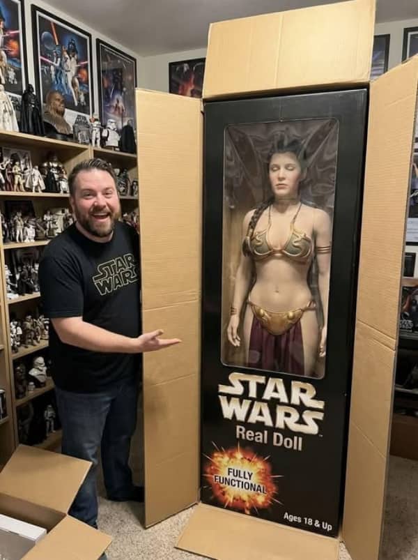 Smiling man standing next to a life-sized Princess Leia Real Doll in a large cardboard box.