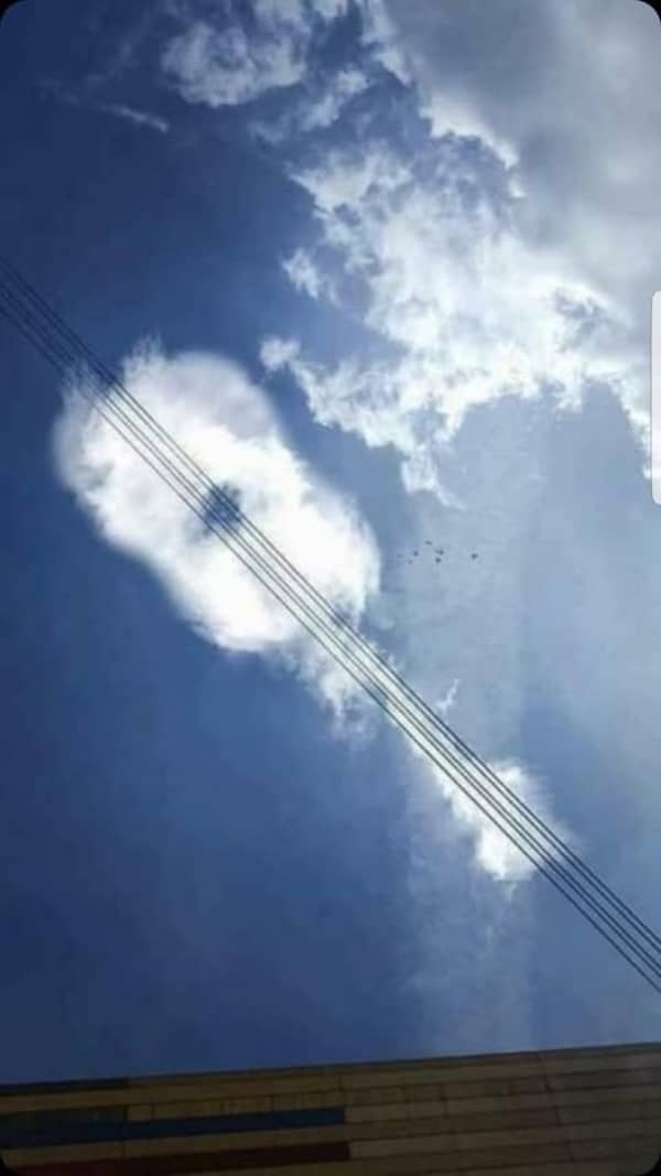 Low angle shot of a cloud shaped like a guitar with power lines as the strings.