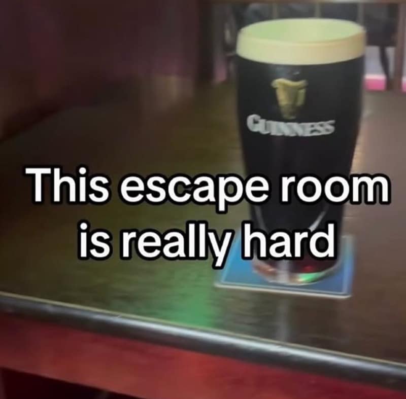 deadpan irish meme showcases a single pint of Guinness sitting on a dark wooden bar top with the ironic, dry caption: "This escape room is really hard."