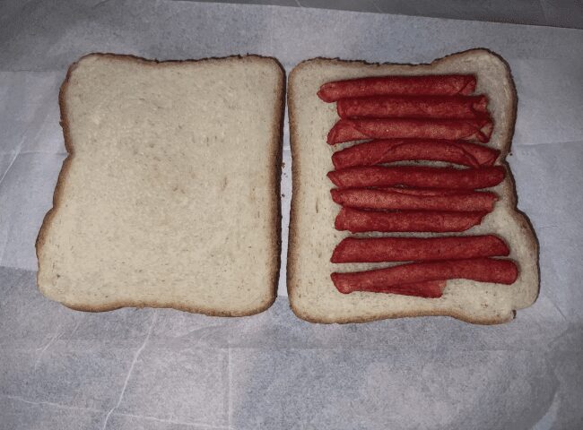 Open-faced sandwich with bright red Takis chips lined up on white bread, a classic struggle meal.