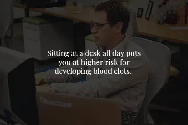 Man sitting at a desk with text explaining the risk of blood clots from sitting all day.