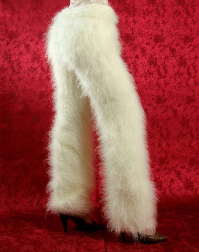 This weird fashion piece shows a pair of shaggy, long-haired white "yeti" pants made of thick faux fur, styled with high heels against a dramatic red background for maximum texture