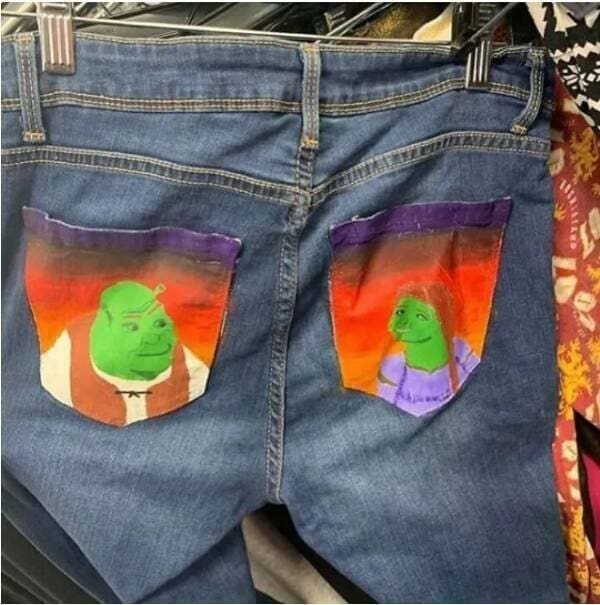 Thrift store weird fashion at its peak: the back pockets of these denim jeans feature hand-painted, slightly distorted portraits of Shrek and Fiona against a sunset backdrop.