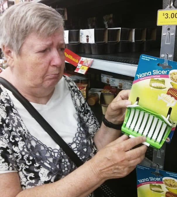 Concerned elderly woman looking at a kitchen gadget called a Nana Slicer for bananas.