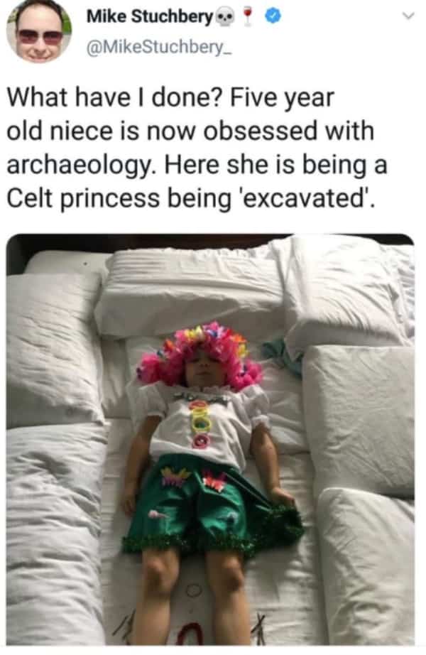 Five-year-old girl dressed as a Celt princess lying on a bed surrounded by pillows.