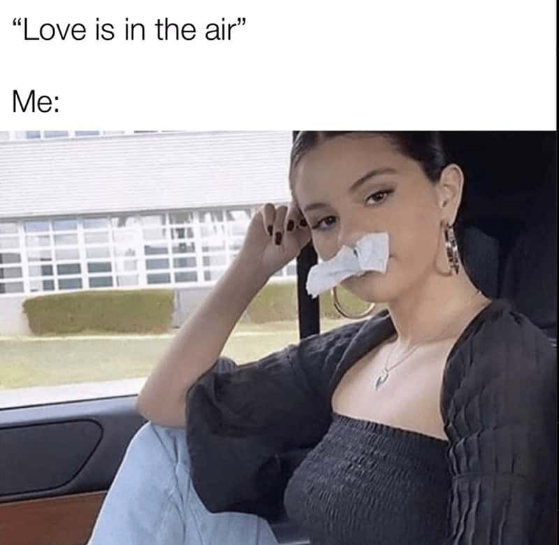 Selena Gomez casually sitting with tissues completely stuffed up her nose in a highly relatable women meme reacting defensively to the phrase love is in the air, wrapping up this first half of memes for women.
