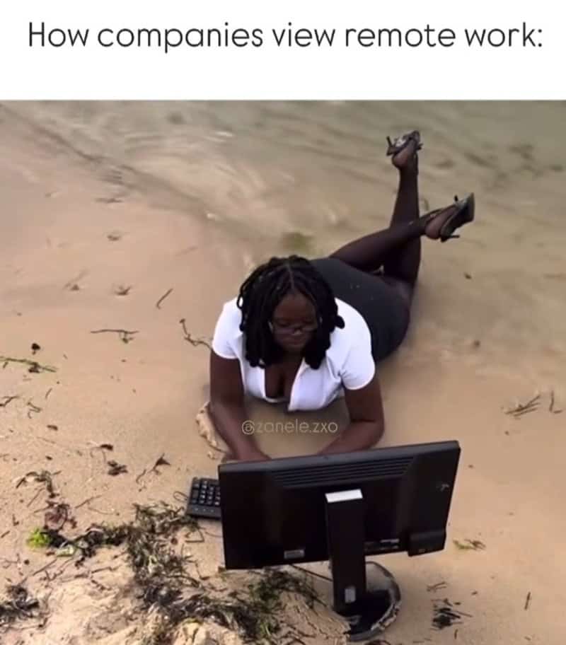 satirical funny work meme titled "How companies view remote work," showing a woman lying in the wet sand at a beach, fully dressed in office wear while typing on a desktop computer monitor and keyboard.