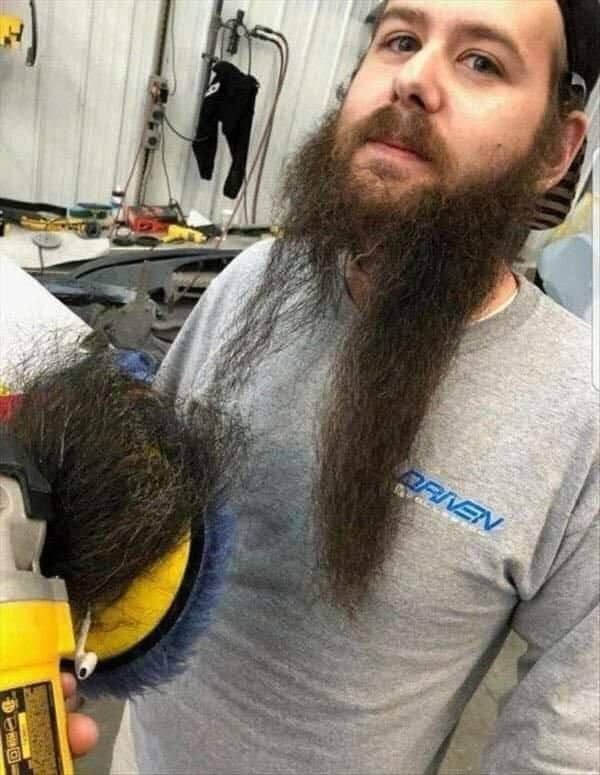 Bearded man in workshop holding a power polisher with a large clump of beard hair.