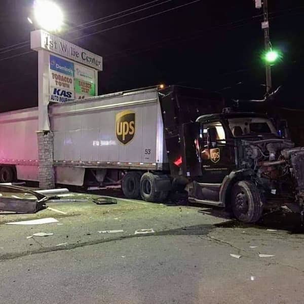 Brown UPS delivery semi-truck crashed into the side of a brick and white building.