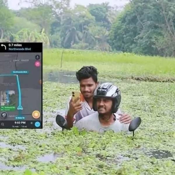Two men on a submerged motorcycle in a flooded field following GPS navigation directions.