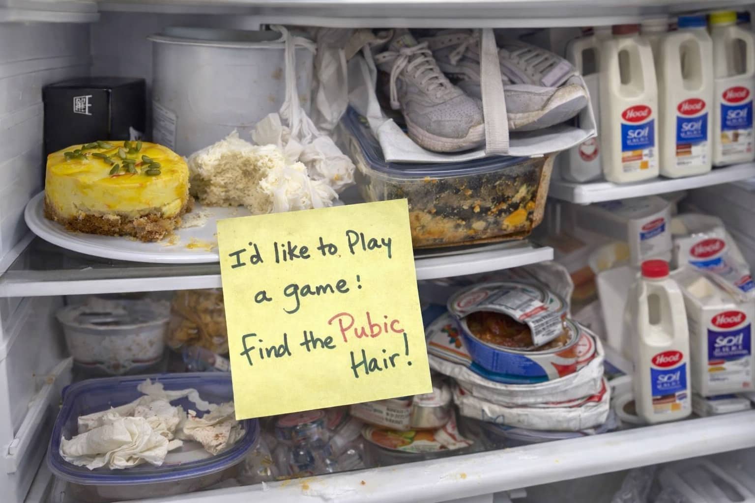 Gross office fridge filled with old food, sneakers, and a sarcastic note about a game.