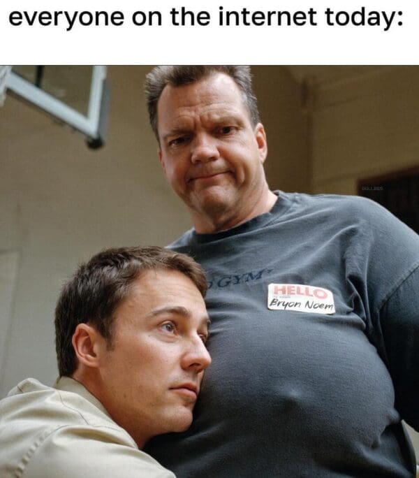 A Kristi Noem husband meme using a movie still of a large-chested man wearing a "Hello My Name Is Bryon Noem" name tag. The man looks down at a smaller man resting his head on his chest, captioned: "everyone on the internet today."