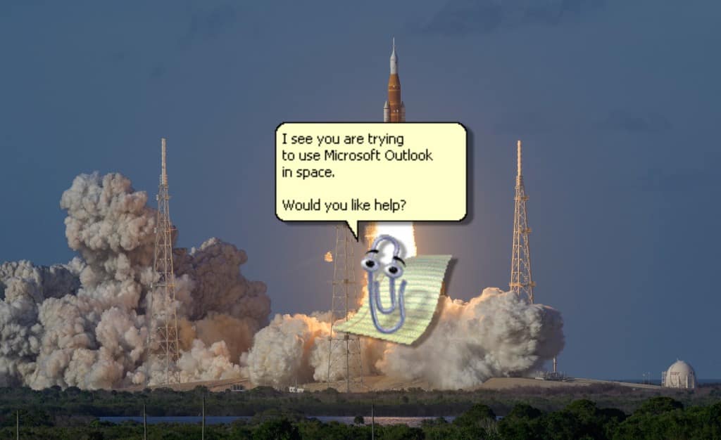 A hilarious artemis ii meme showing the SLS rocket ascending through massive clouds of smoke, with a pixelated Microsoft Clippy superimposed in the foreground asking, "I see you are trying to use Microsoft Outlook in space. Would you like help?"