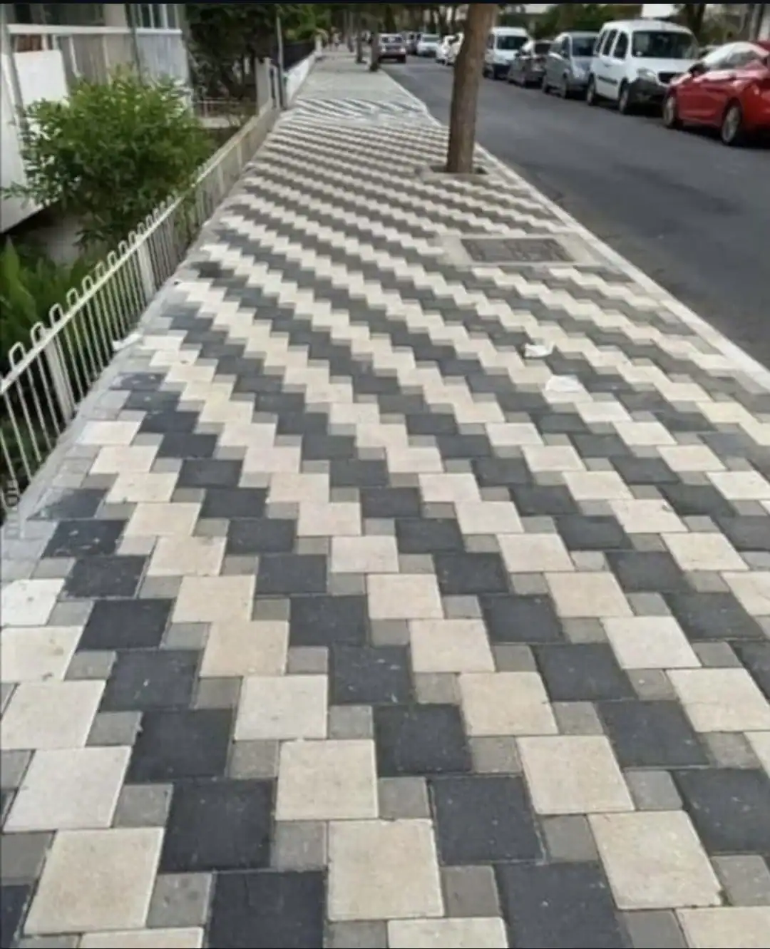 dizzying example of awful taste but great execution in urban design: a long sidewalk paved with a complex, perfectly aligned black and white zigzag chevron pattern that creates a disorienting optical illusion for pedestrians.