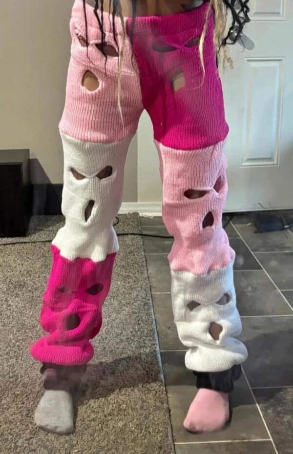 A pair of high-waisted leggings constructed entirely from multiple pink, magenta, and white knit ski masks sewn together, with the original eye and mouth holes serving as "distressed" cutouts along the legs.