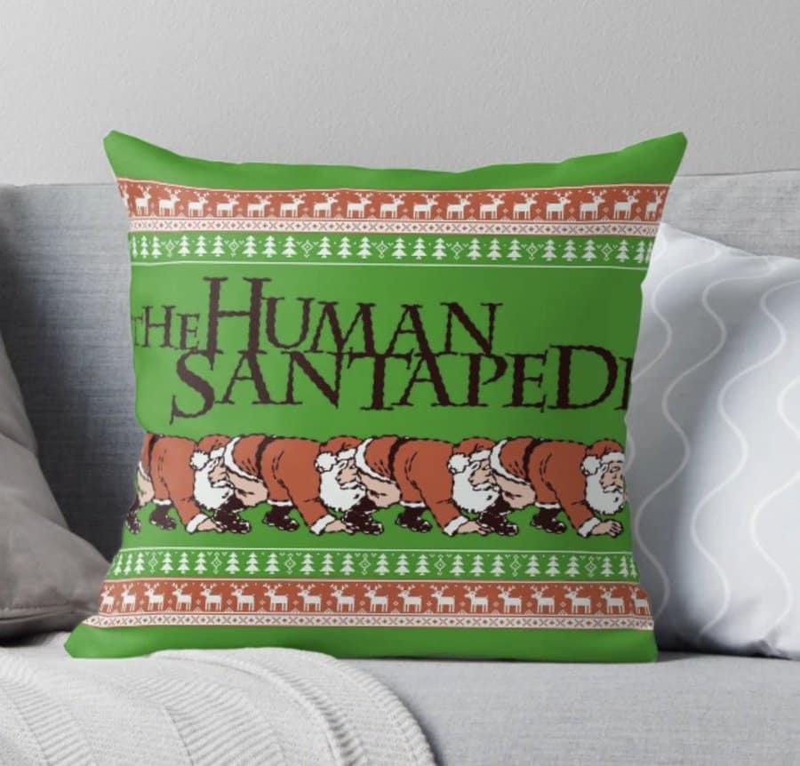 holiday-themed throw pillow featuring a parody graphic titled "The Human Santapede." It depicts a line of cartoon Santas joined together in the style of the infamous horror movie poster.