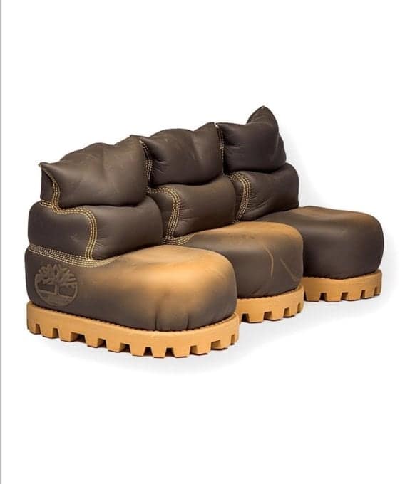 A three-seater living room sofa meticulously crafted to resemble three giant, side-by-side brown Timberland work boots, complete with heavy rubber treads and visible stitching.