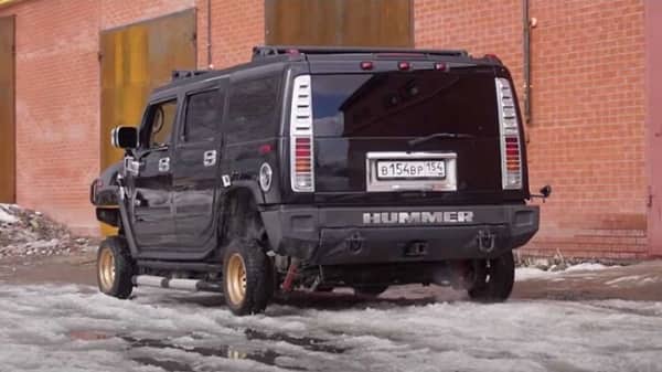 Black Hummer H2 with mismatched gold rear wheels and questionable DIY suspension modification
