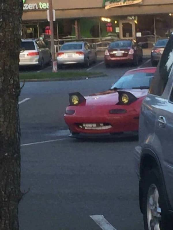 Red Mazda RX-7 with pop-up headlights raised making a bizarre angry face expression
